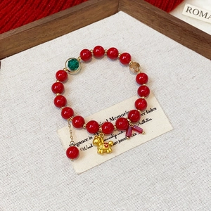 Detail of red beaded bracelet with golden animal pendant and faceted crystal accents