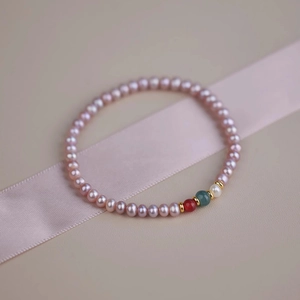 Macro detail of freshwater pearl bracelet with red agate beads and gold accents