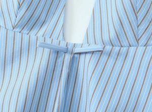 Detail of blue and white striped top featuring deep V-neck and central bow decoration
