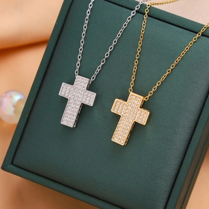 Fashionable micro-paved cross necklaces in gold and silver finish on a green jewelry box
