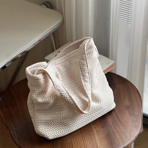 Detailed close-up of V-shaped woven texture on a beige canvas shoulder tote bag