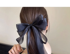 Close-up of oversized black organza bow hair clip featuring elegant layered mesh fabric