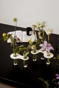 Artistic close-up of creative test tube vase with wavy white base and glass vials