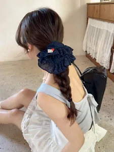 Detail of navy blue polka dot ruffle scrunchie styled in hair with handmade label tag