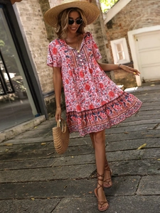 Detail view of pink floral Bohemian maxi dress with V-neck and ruffled hem in outdoor setting