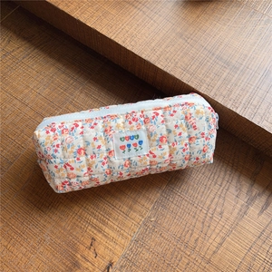 Detailed close-up of quilted floral cotton pouch with colorful pattern and heart patch