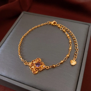 Close-up of golden beaded bracelet with purple gemstone and delicate heart pendant detail