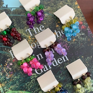 Macro view of resin grape tassel earrings showing various colors on a magazine background