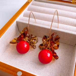 Détail macro de pétales de fleurs ambrées et perles rouges sur boucles d'oreilles dorées