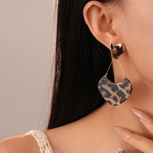 Gros plan de boucles d'oreilles cœur léopard rétro avec clous dorés portées par un mannequin