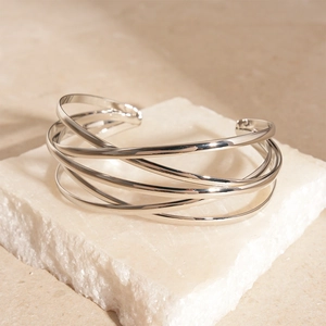 Close-up of polished silver multi-layer geometric open cuff bracelet on white stone