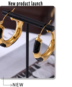Detailed macro view of gold plated thick hoop earrings with black enamel leopard print oil drip