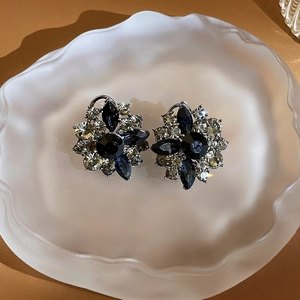Detailed view of flower-shaped stud earrings with black and champagne stones on a tray