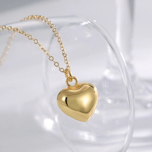 Minimalist gold heart pendant necklace displayed elegantly on a glass rim with high shine
