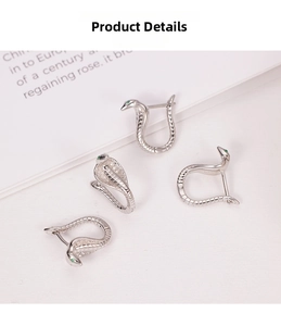 Detail of silver cobra hoop earrings with scale texture and green gemstone eyes