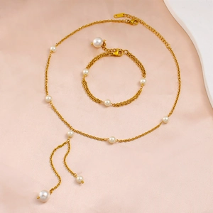 Elegant gold pearl necklace and bracelet set displayed on soft pink silk fabric