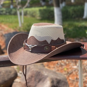 Western straw cowboy hat with cattle head emblem on wooden fence for outdoor travel