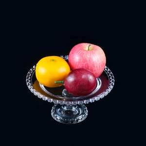 Detail of transparent glass fruit tray with bead relief edges and a sturdy footed base