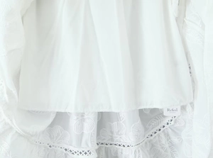 Détail de la broderie florale blanche et de l'ourlet en dentelle ajourée sur la jupe