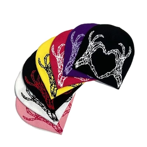 Knitted beanie with skull hand heart pattern in multiple colors including black and purple