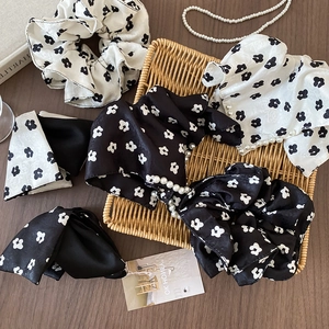 Detail view of black and white floral satin scrunchies with pearls and bow accents