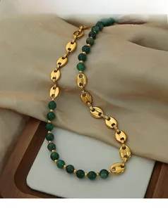 Detailed close-up of gold pig-nose chain links and green agate beads on silk