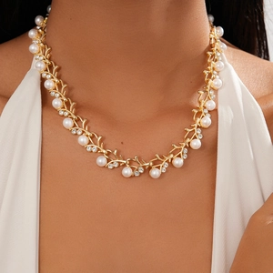 Macro detail of vintage gold vine necklace with faux pearls and sparkling rhinestones