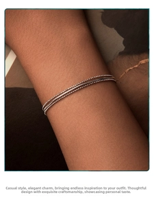Detail of layered s925 silver beaded and snake chain bracelet on female wrist