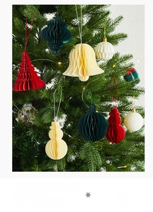Close-up of honeycomb paper Christmas tree and snowman ornaments on a lit tree