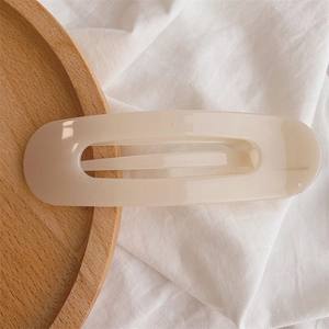 Macro shot of minimalist cream resin hair clip with hollow design on white cloth