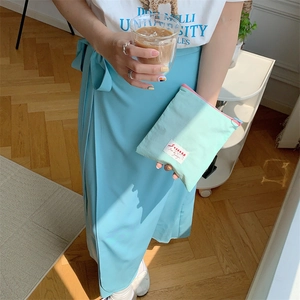 Mint green portable storage bag with pink zipper held by hand in a lifestyle setting