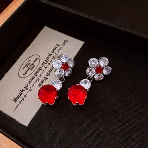 Close-up of vintage flower drop earrings with red zircon and white crystals on a jewelry box