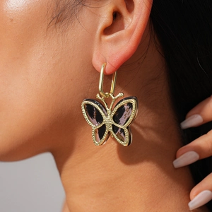 Close-up of golden butterfly pendant earring with tortoise pattern on a female model