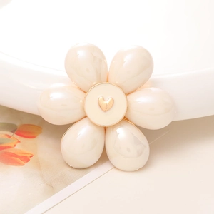 Macro shot of cream floral DIY charm with pearl petals and a golden heart center