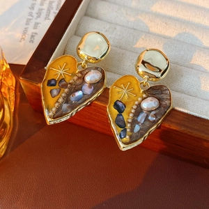 Detail of vintage heart earrings with gold plating, shell inlay and pearls on wood tray
