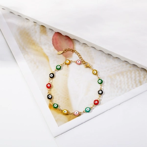 Detail of multi-color enamel evil eye beads on a golden stainless steel chain bracelet