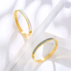 Close-up of gold hinged bracelets featuring white and grey enamel inlay on geometric stands