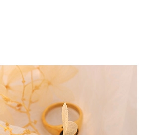 Close-up of golden ring featuring a black gemstone inlay on textured beige background