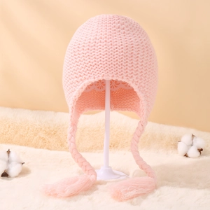 Detail of pink knitted baby hat with earflaps, braided tassels and soft lining