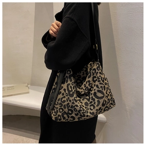 Close-up of leopard print tote bag fabric with black leather strap and gold hardware
