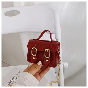 Close-up of red jelly material texture and gold metallic buckle on mini satchel bag