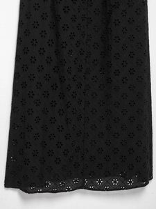 Detail of black eyelet embroidery with floral geometric patterns on summer dress fabric