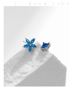 Detail of asymmetric S925 silver earrings with blue sapphire flower and square studs