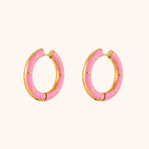 Macro detail of 18K gold-plated wheel hoop earrings with pink enamel drip-oil finish