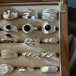 Close-up of assorted silver metal rings with black onyx and pearls in a wooden jewelry box