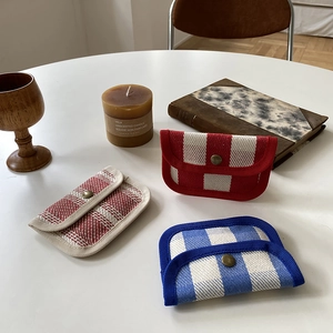 Three woven coin purses in red and blue patterns displayed with vintage home decor items