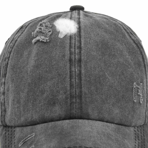 Macro detail of distressed washed grey baseball cap showing frayed holes and fabric texture