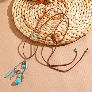 Detail of bohemian long necklace with turquoise stones, metal feathers and suede cord
