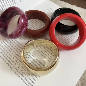Selection of chunky resin and gold metal bangles styled on artistic book pages