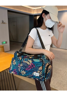 Deep blue travel bag with tropical leaf print and durable shoulder strap shown on model